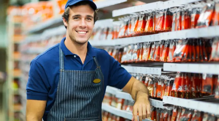 Foto de trabajador en una gondola de ferretería sonriendo